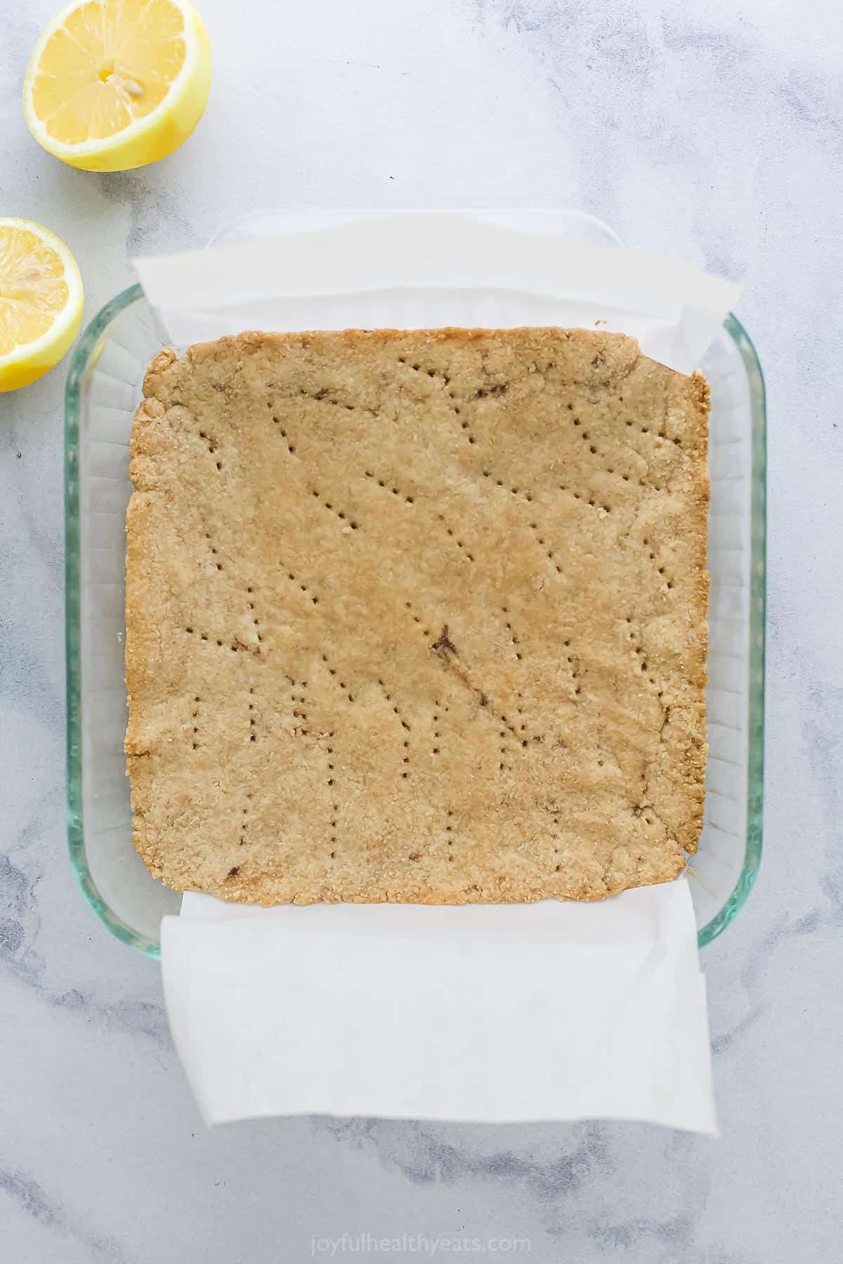 A maple almond crust in an 8x8-inch baking dish with small holes poked throughout it