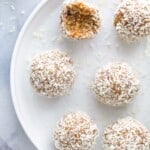 Coconut protein bites on a white plate with a raised rim