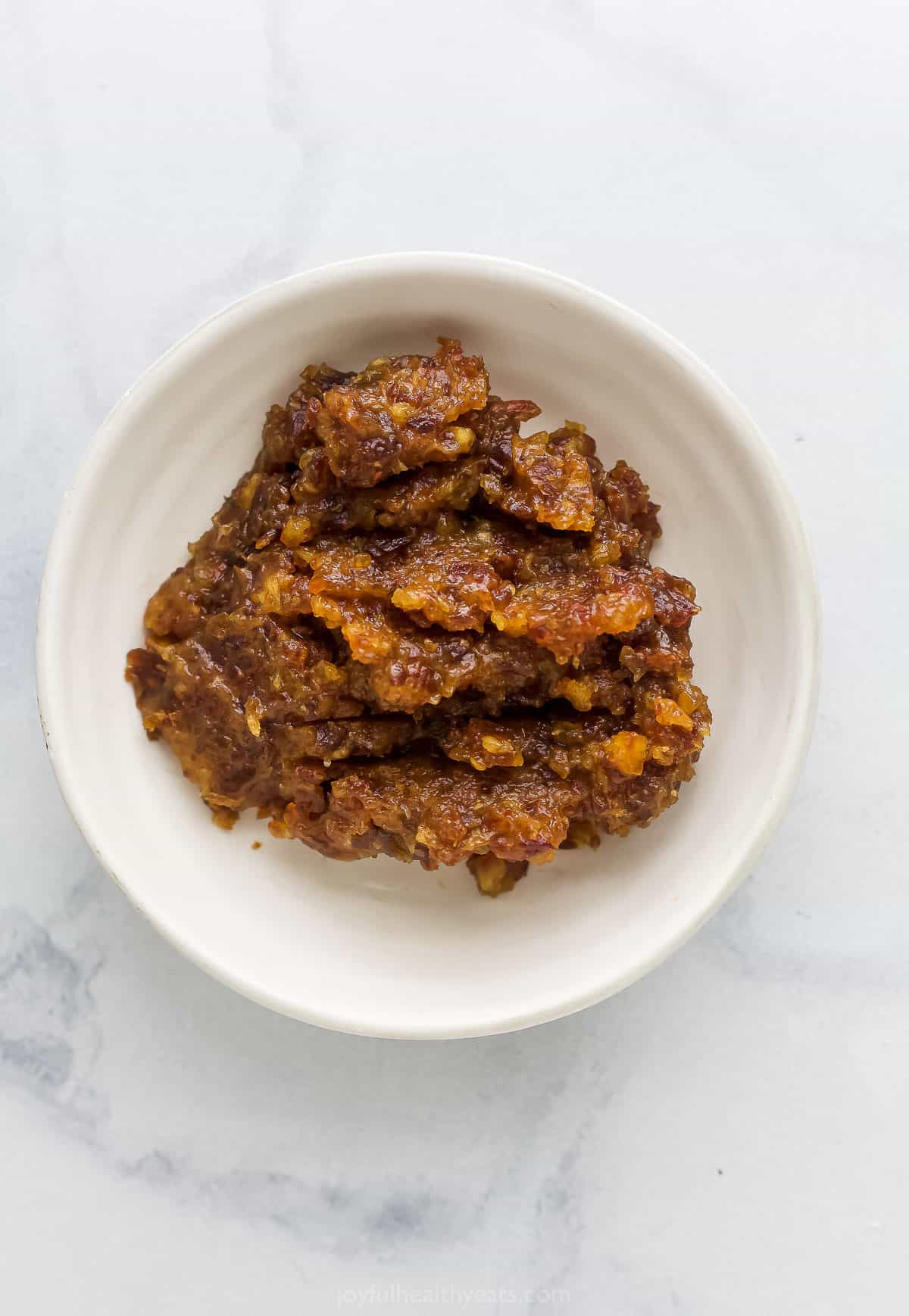 The blended date and warm water mixture in a small dish on a kitchen countertop