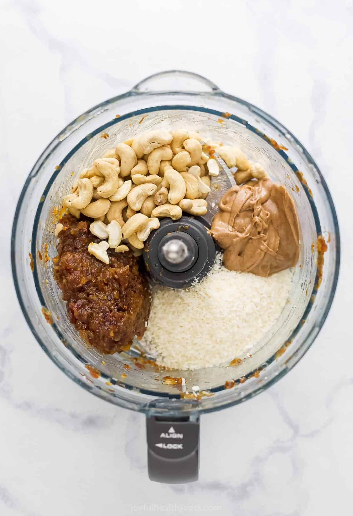 The blended date mixture in a food processor with the cashews, almond butter and coconut