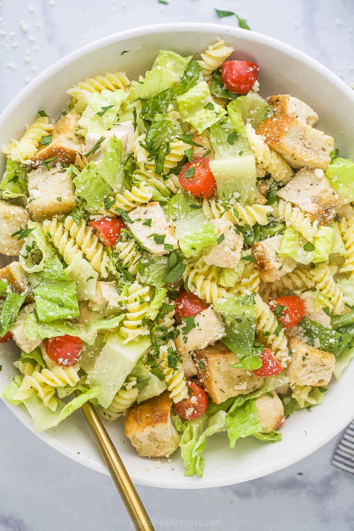 An overhead shot of a serving bowl full of salad on a marble countertop