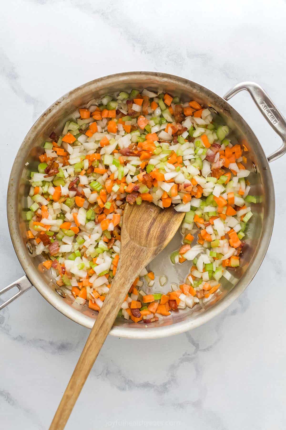 Carrots, onions, celery, and bacon in a saute pan