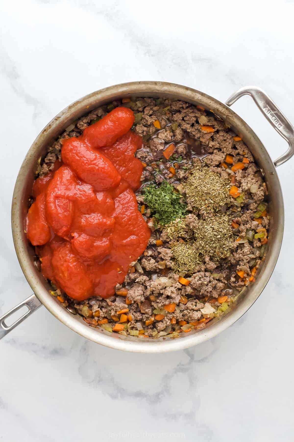 Saute pan with cooked ground beef, vegetables, canned tomatoes, and ground spices