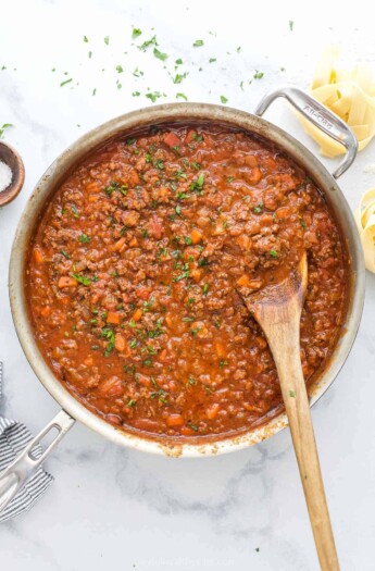 Ragu sauce simmering in pot with beef, vegetables, and tomato sauce