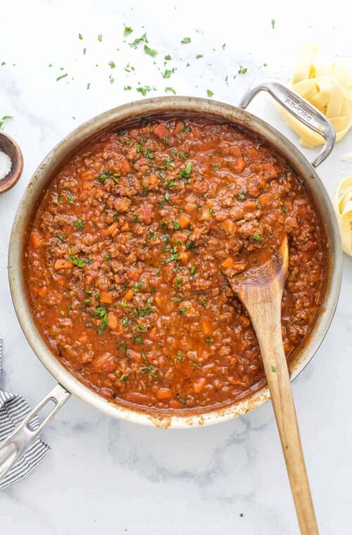 Ragu sauce simmering in pot with beef, vegetables, and tomato sauce