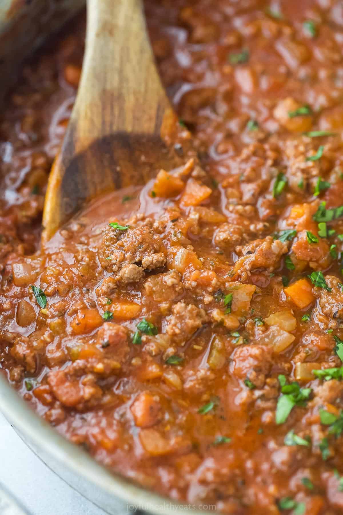 Ragu sauce simmering in pan with beef, vegetables, and tomato sauce