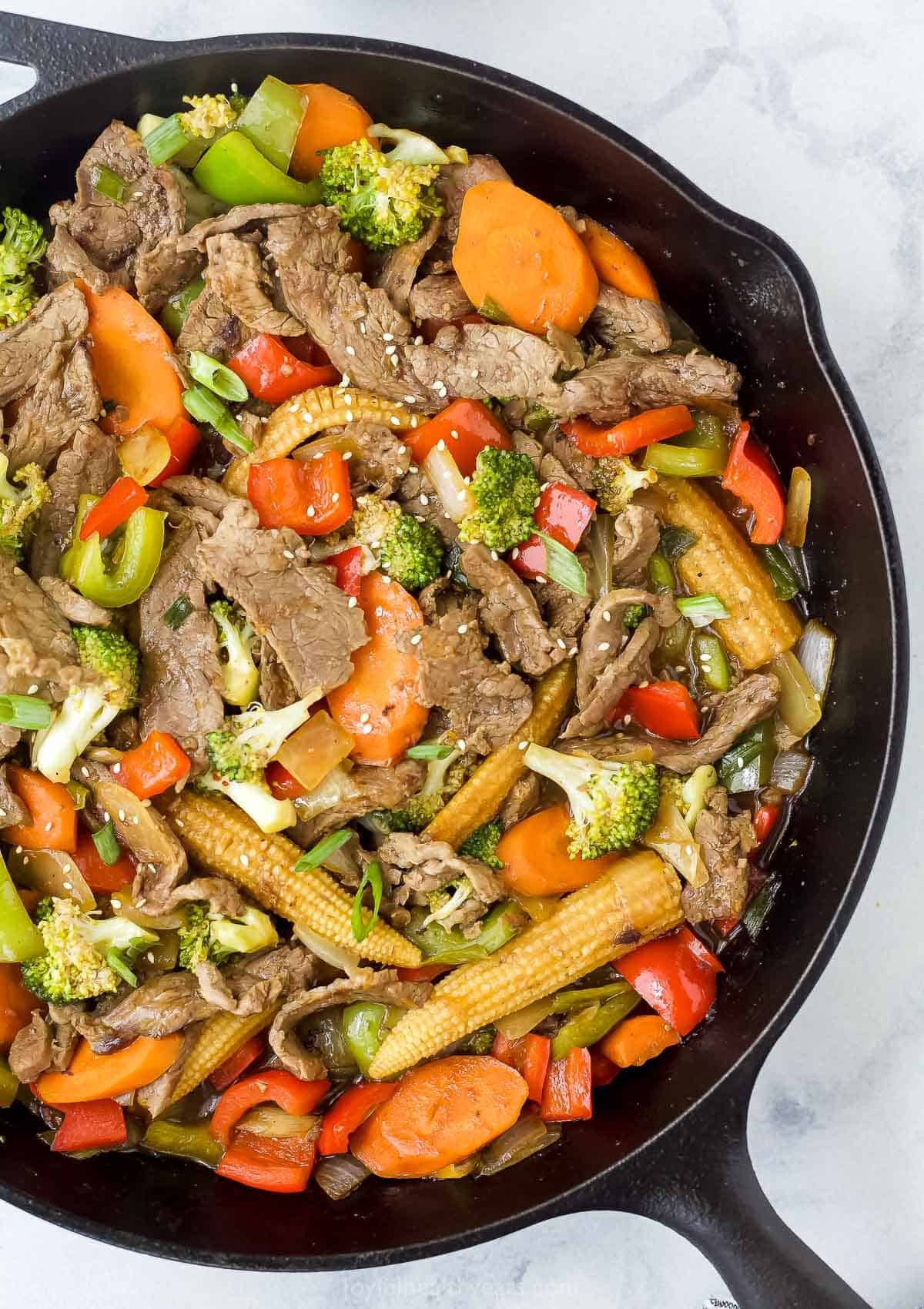 Hunan beef made with vegetables and streak strips in a cast iron skillet