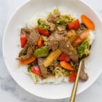 beef mixed with vegetables served on rice on a white plate