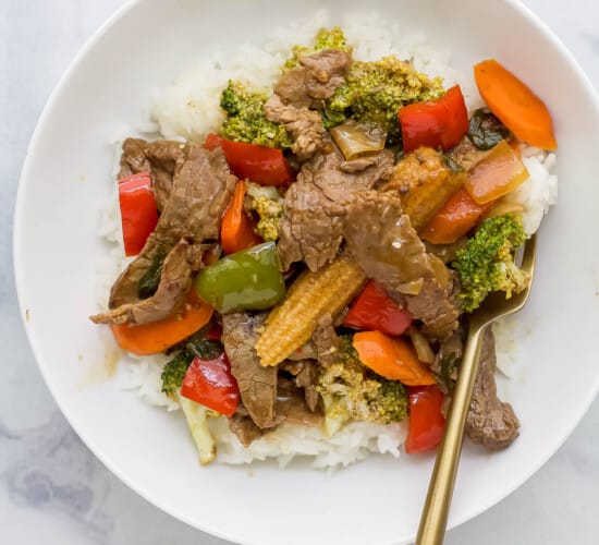 beef mixed with vegetables served on rice on a white plate