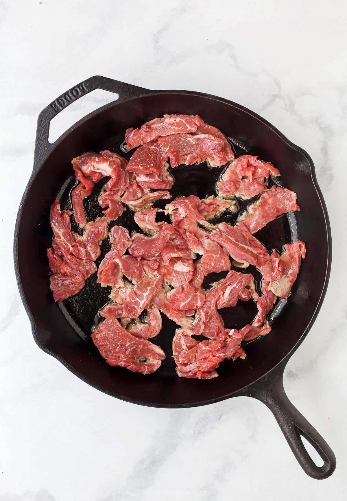 beef strips in a cast iron skillet