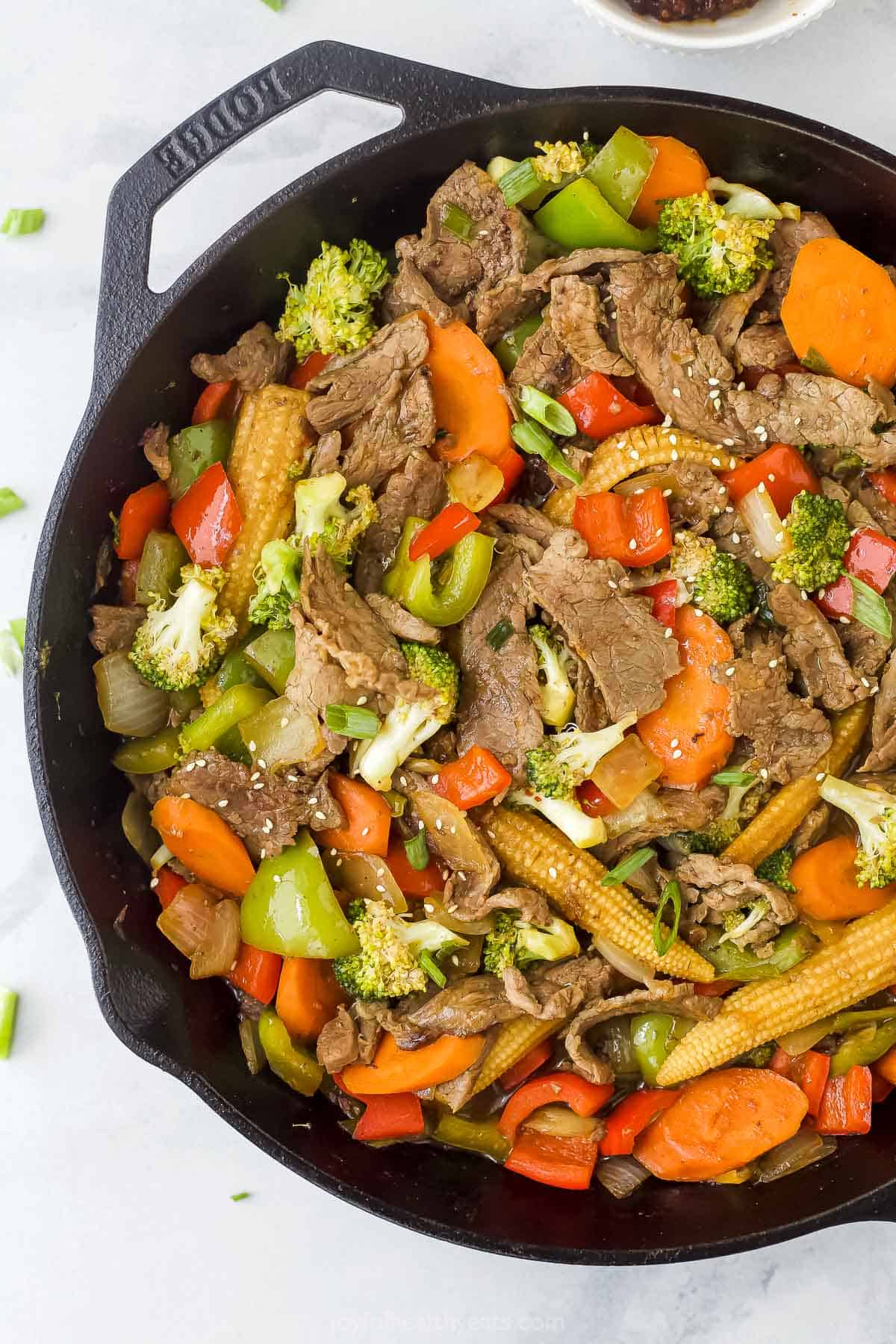 Hunan beef made with vegetables and streak strips in a cast iron skillet