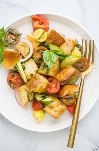 A plate of panzanella salad on a white and gray marble countertop