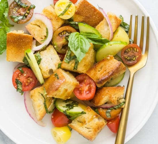 A plate of panzanella salad on a white and gray marble countertop