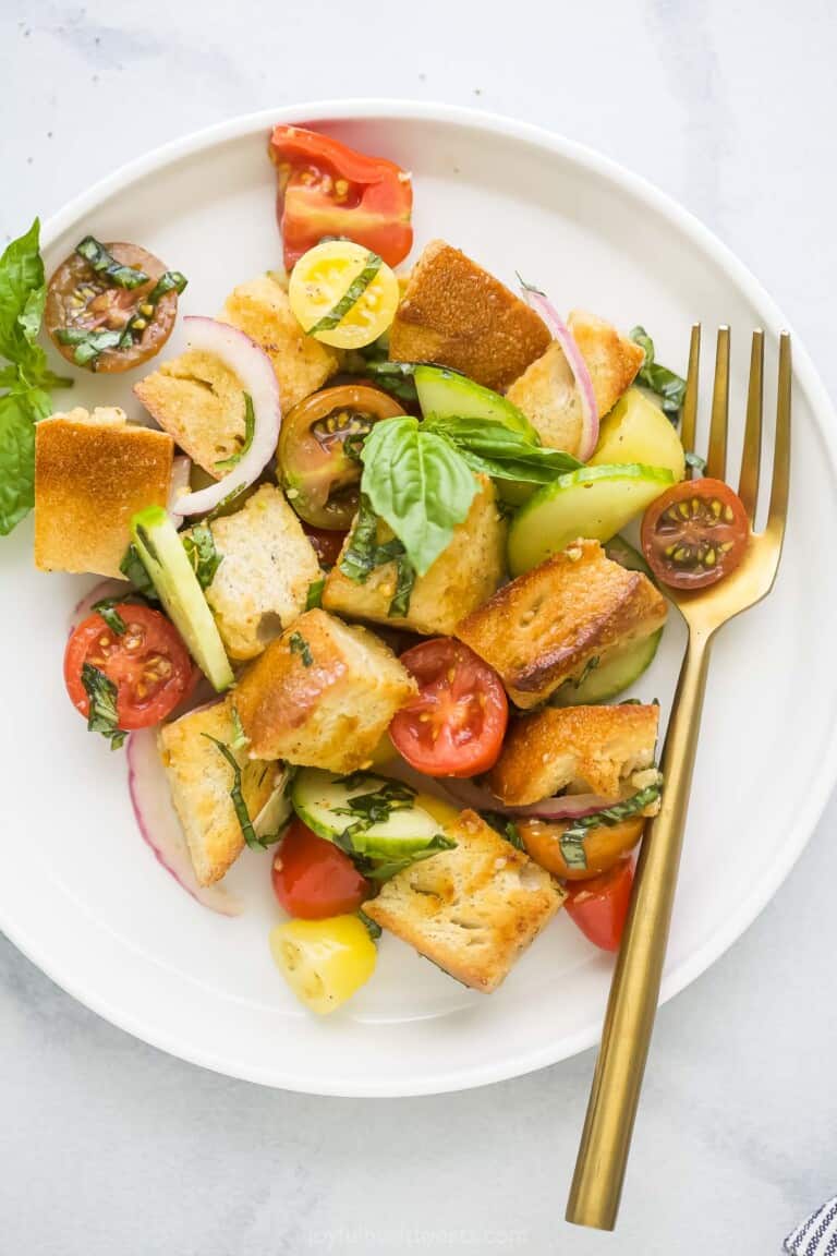 A plate of panzanella salad on a white and gray marble countertop