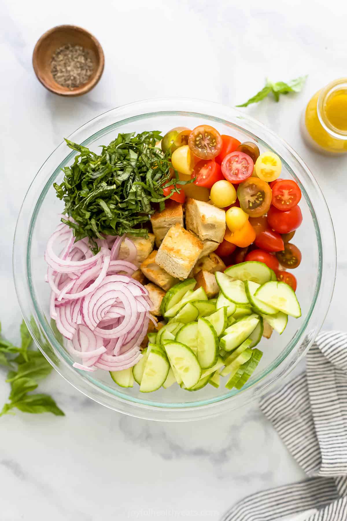 All of the prepared salad ingredients inside of a large glass bowl