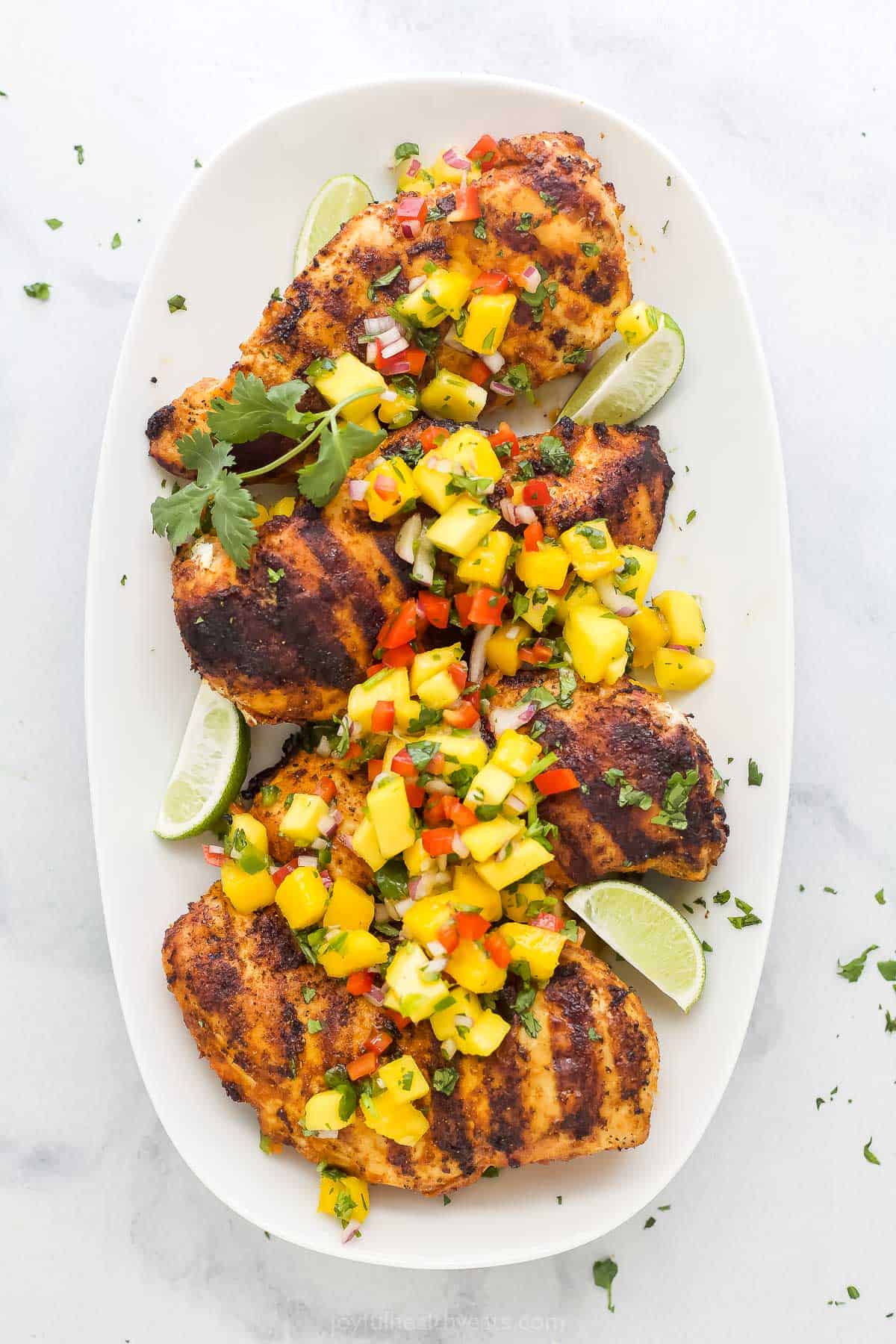 A platter full of mango chicken on a marble kitchen countertop