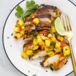 A plate of garlic lime grilled chicken topped with spicy mango salsa