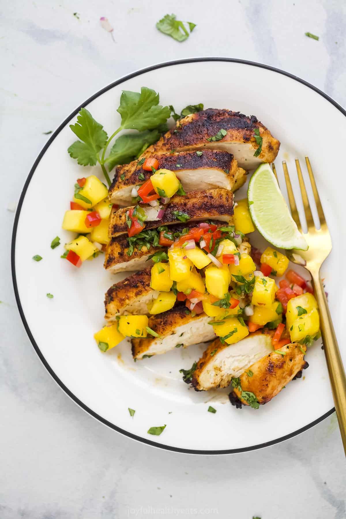 A plate of garlic lime grilled chicken topped with spicy mango salsa