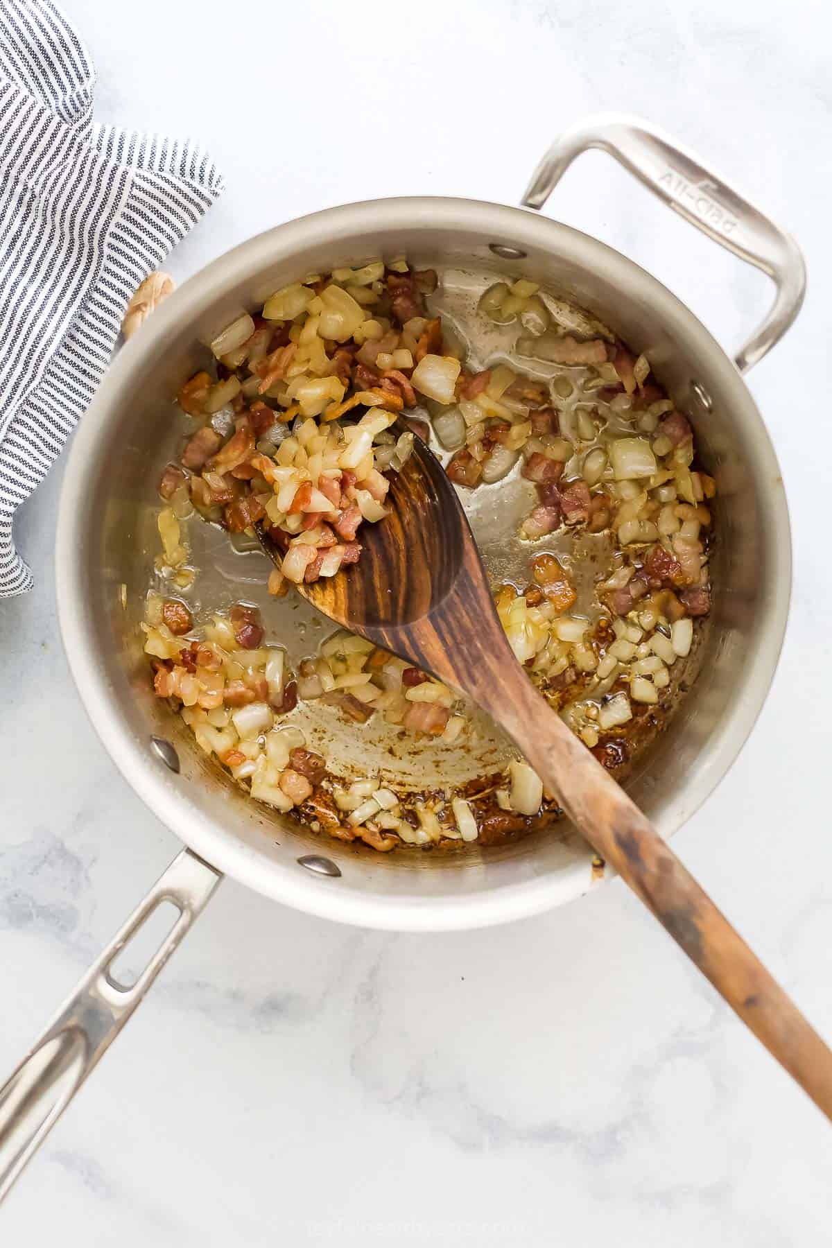 Bacon, onions and garlic sautéing in a large metal saucepan