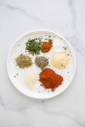 A plate on a marble countertop holding all of the blackening spice ingredients.