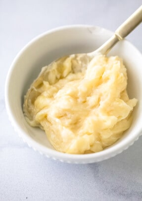 Homemade honey butter inside of a small dish with a spoon being used to stir it.