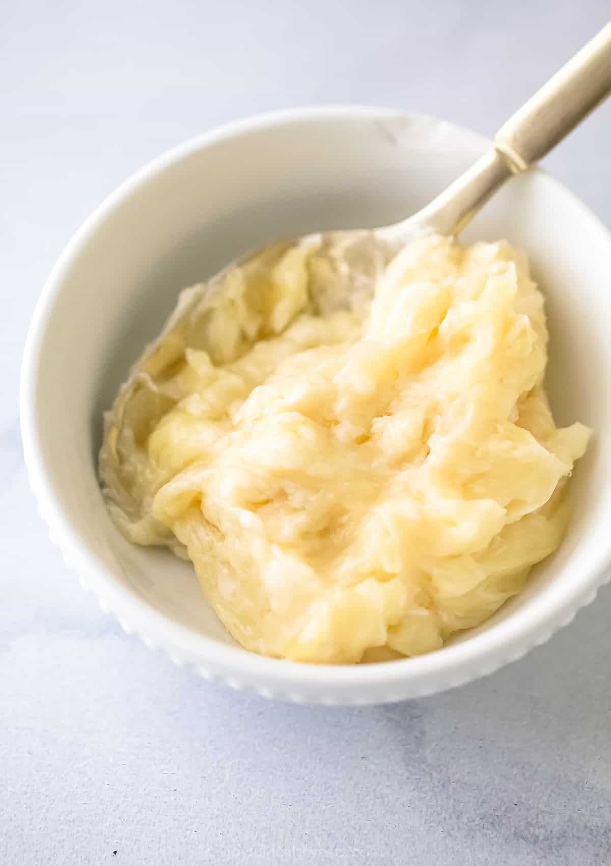 Homemade honey butter inside of a small dish with a spoon being used to stir it