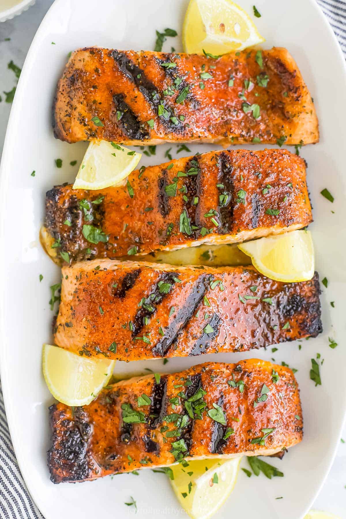 Four grilled fish fillets lined up on a long serving platter