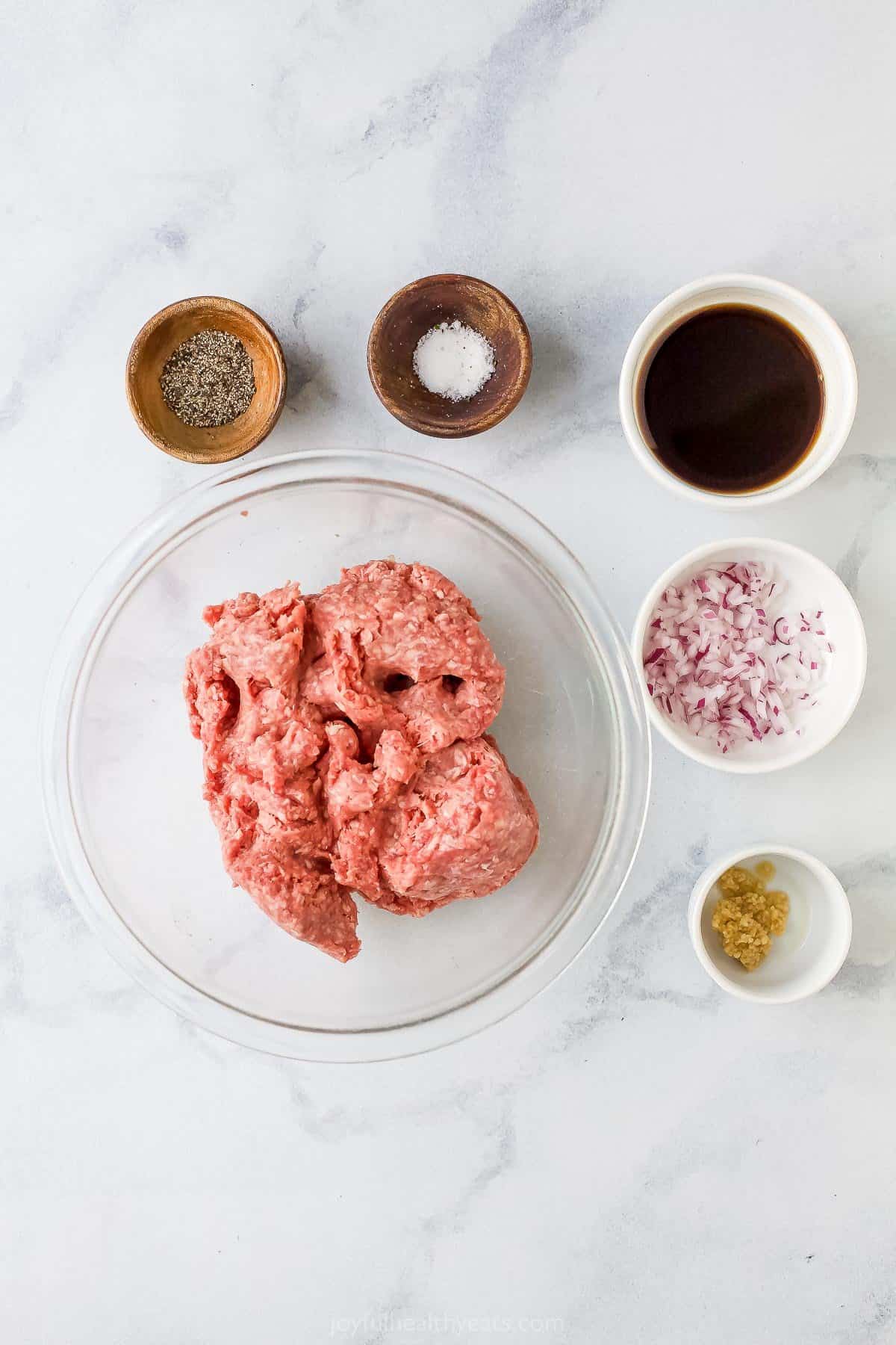 Ingredients to make air fryer burgers like ground beef, worcestershire sauce, red onions, garlic, salt, and pepper