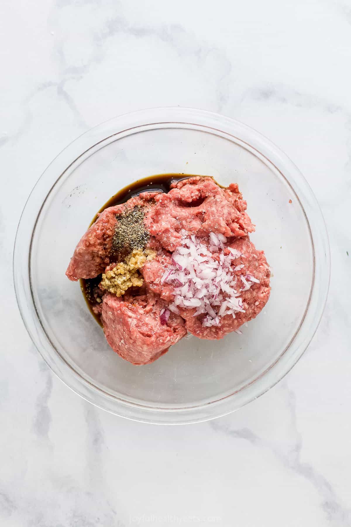 Bowl with ground beef and ingredients to make hamburgers