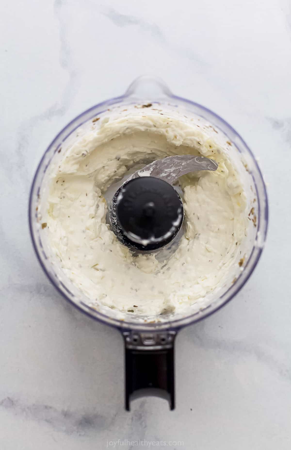 Whipped feta inside of a small food processor on a kitchen countertop