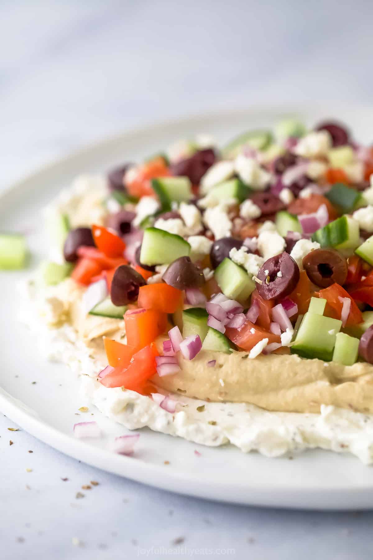 A close-up shot of Mediterranean 7 layer dip on a flat white plate