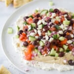 A plate of Mediterranean 7 layer dip on top of a marble counter