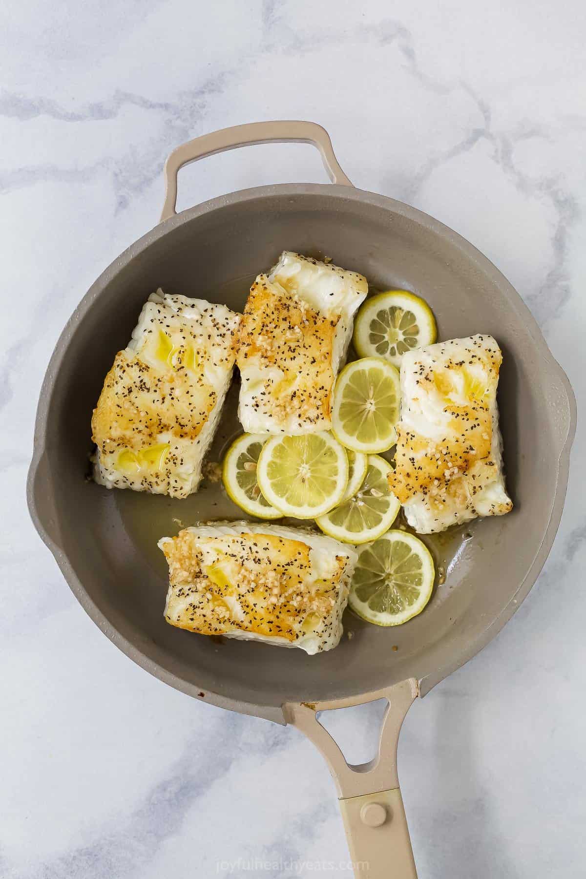 seasoned sea bass in a pan with lemon and ghee