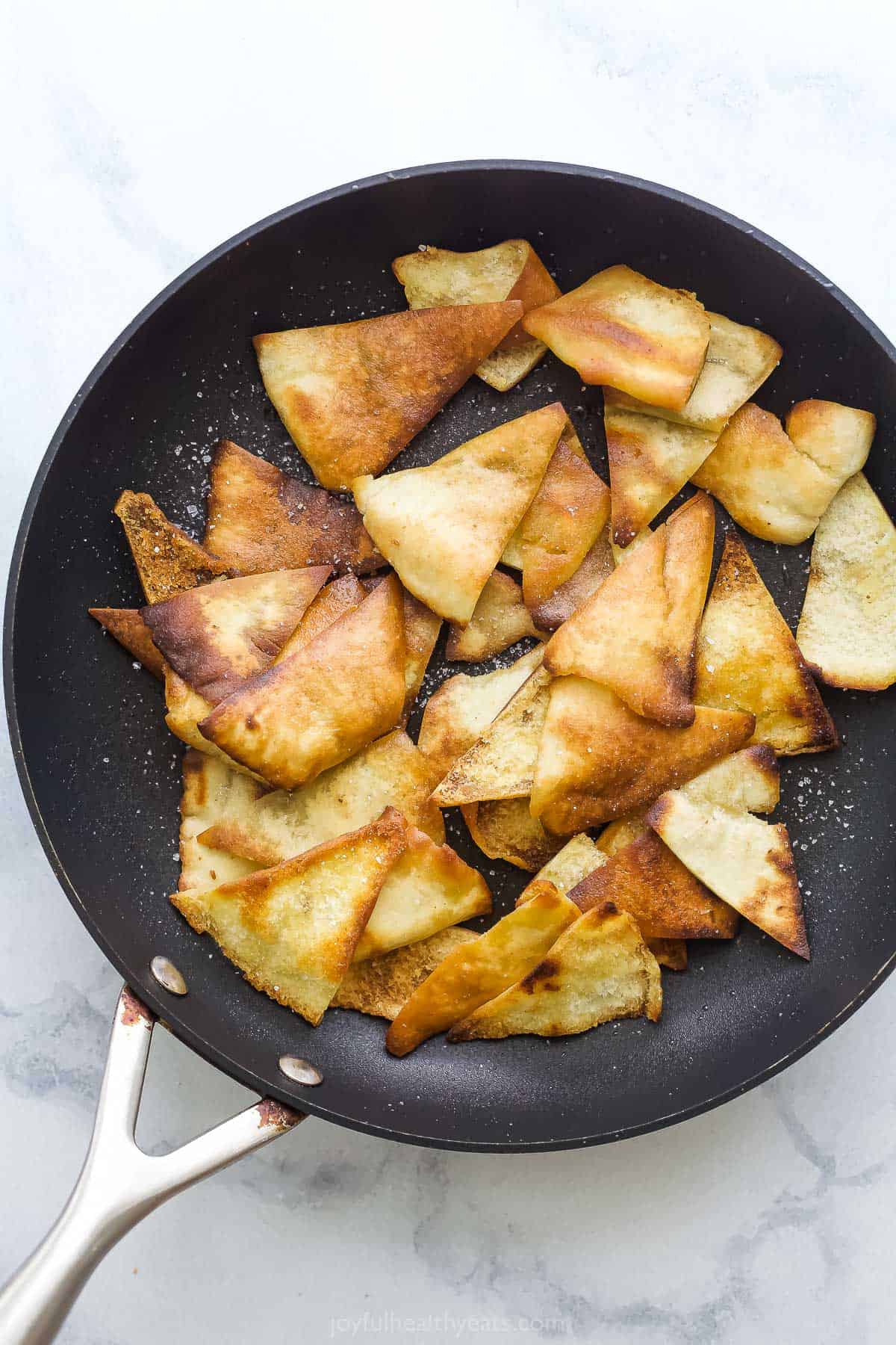 Fried pita croutons inside of a black skillet with a metal handle