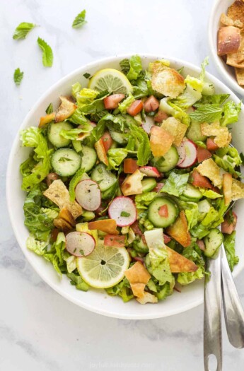 A Lebanese crouton salad on a kitchen countertop with a few bits of chopped parsley beside it