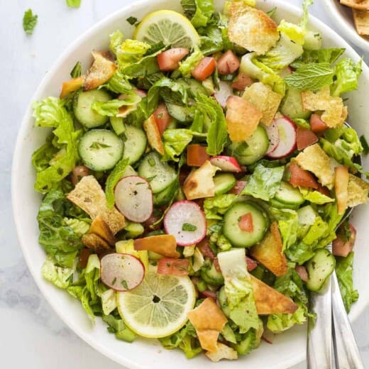 A Lebanese crouton salad on a kitchen countertop with a few bits of chopped parsley beside it