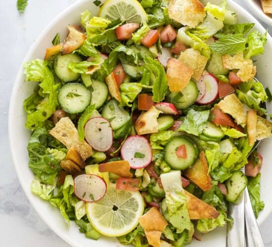 A Lebanese crouton salad on a kitchen countertop with a few bits of chopped parsley beside it