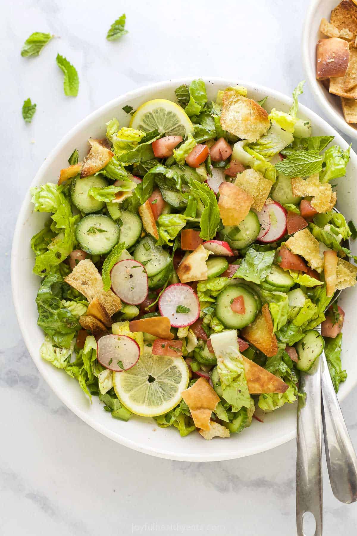 A Lebanese crouton salad on a kitchen countertop with a few bits of chopped parsley beside it