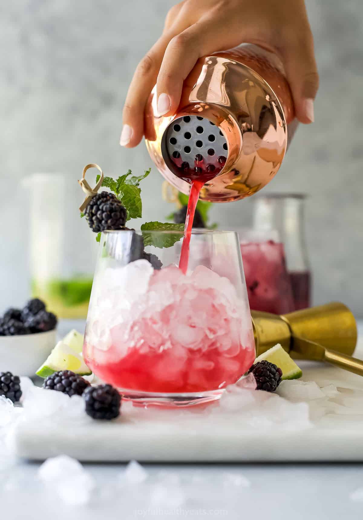 The margarita mixture being strained into a glass filled with crushed ice