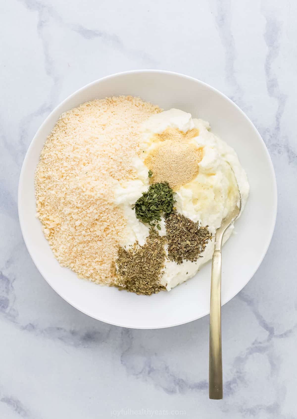 All of the ricotta filling ingredients inside of a mixing bowl with a spoon