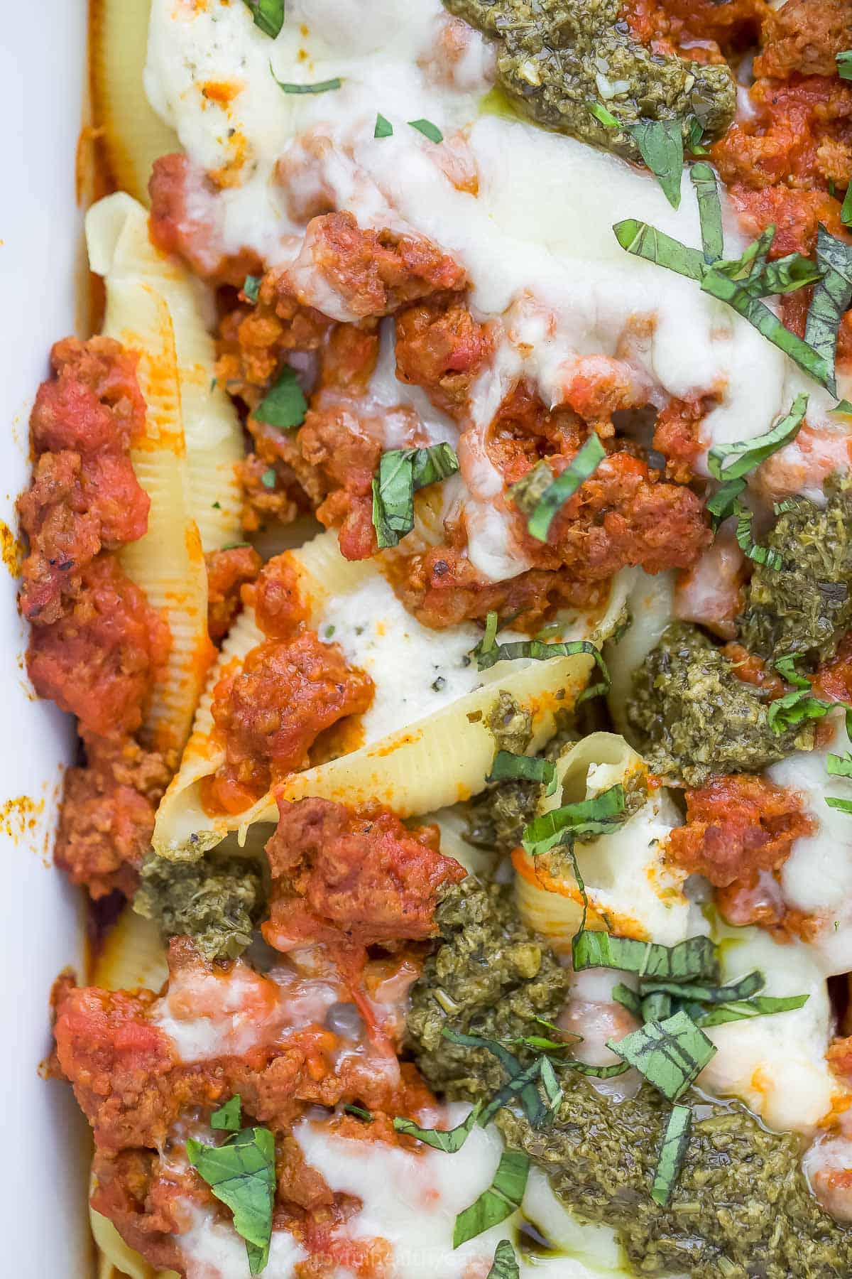 A close-up shot of ricotta stuffed shells with meat sauce inside of a baking dish