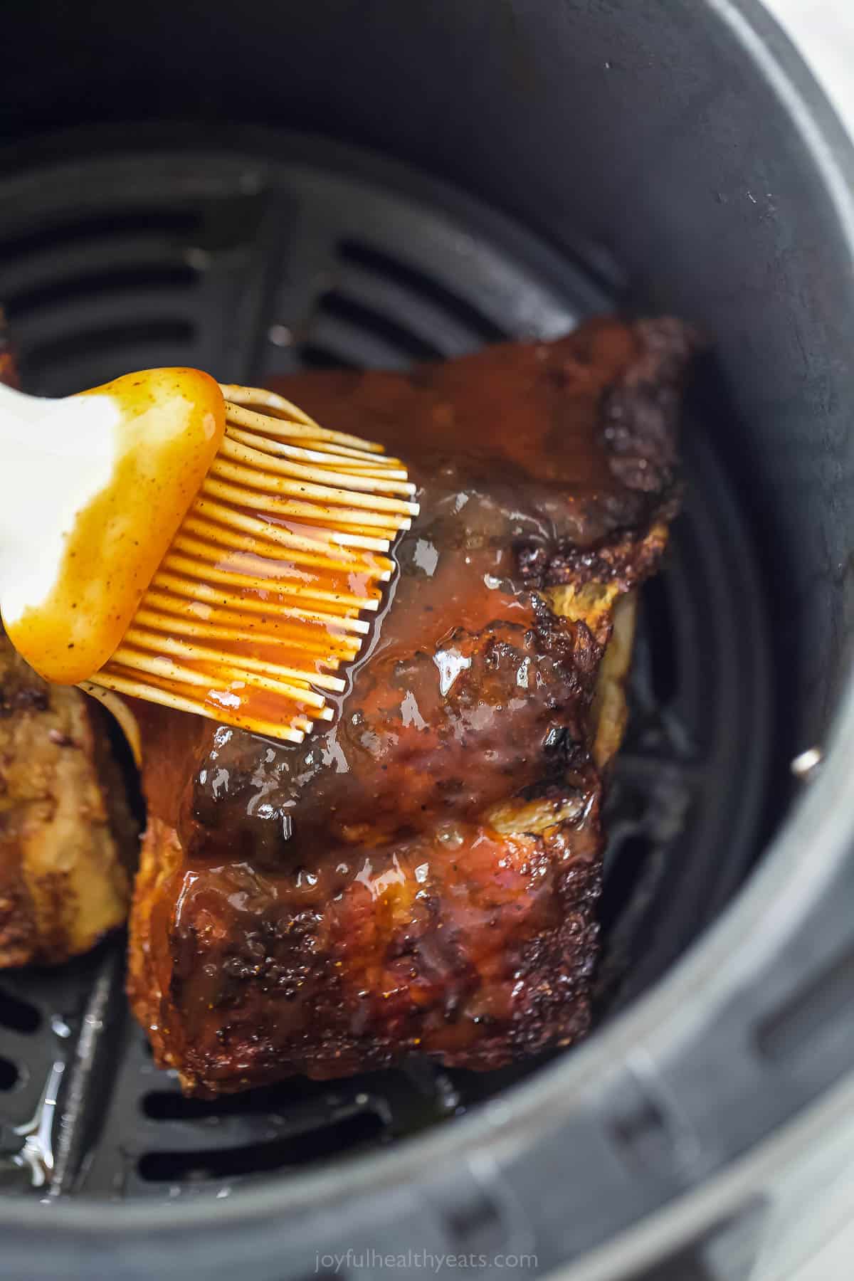 brushing sauce on ribs in an air fryer