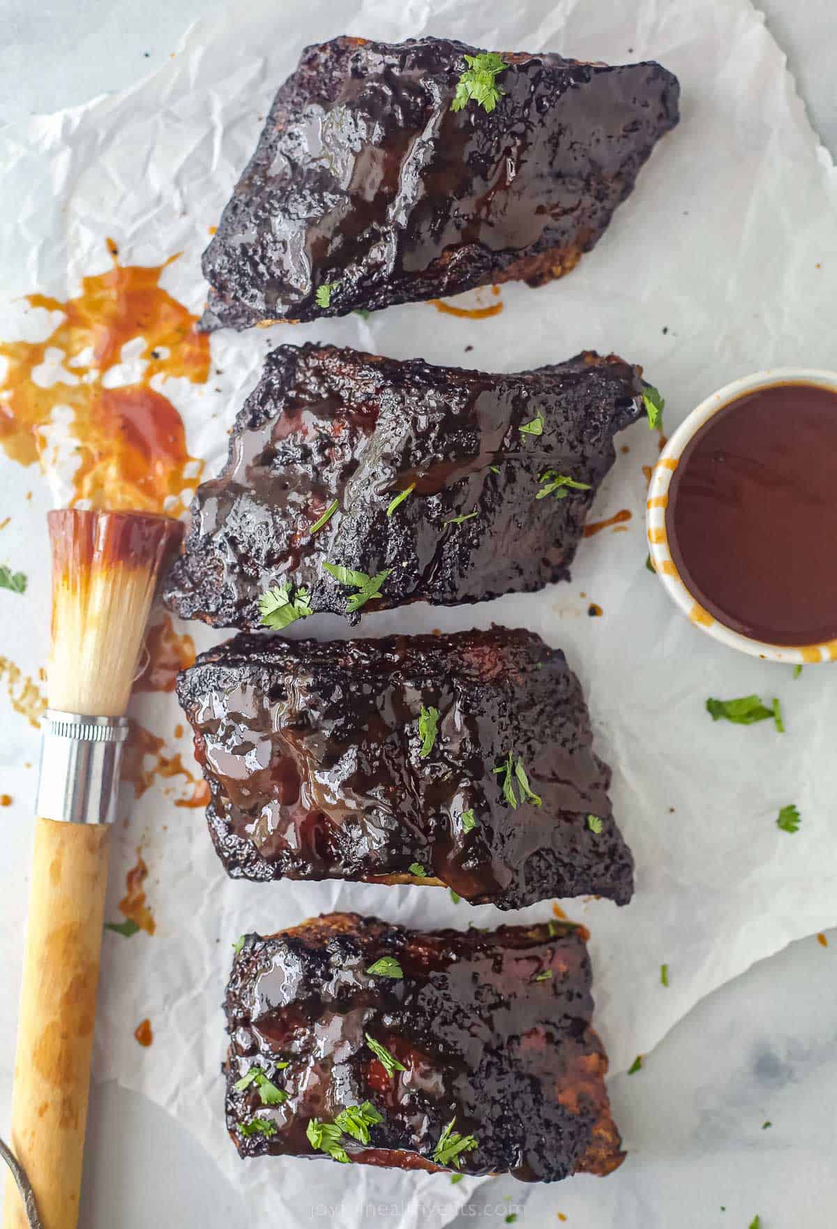 Baby Back BBQ Ribs next to a BBQ brush and side of sauce