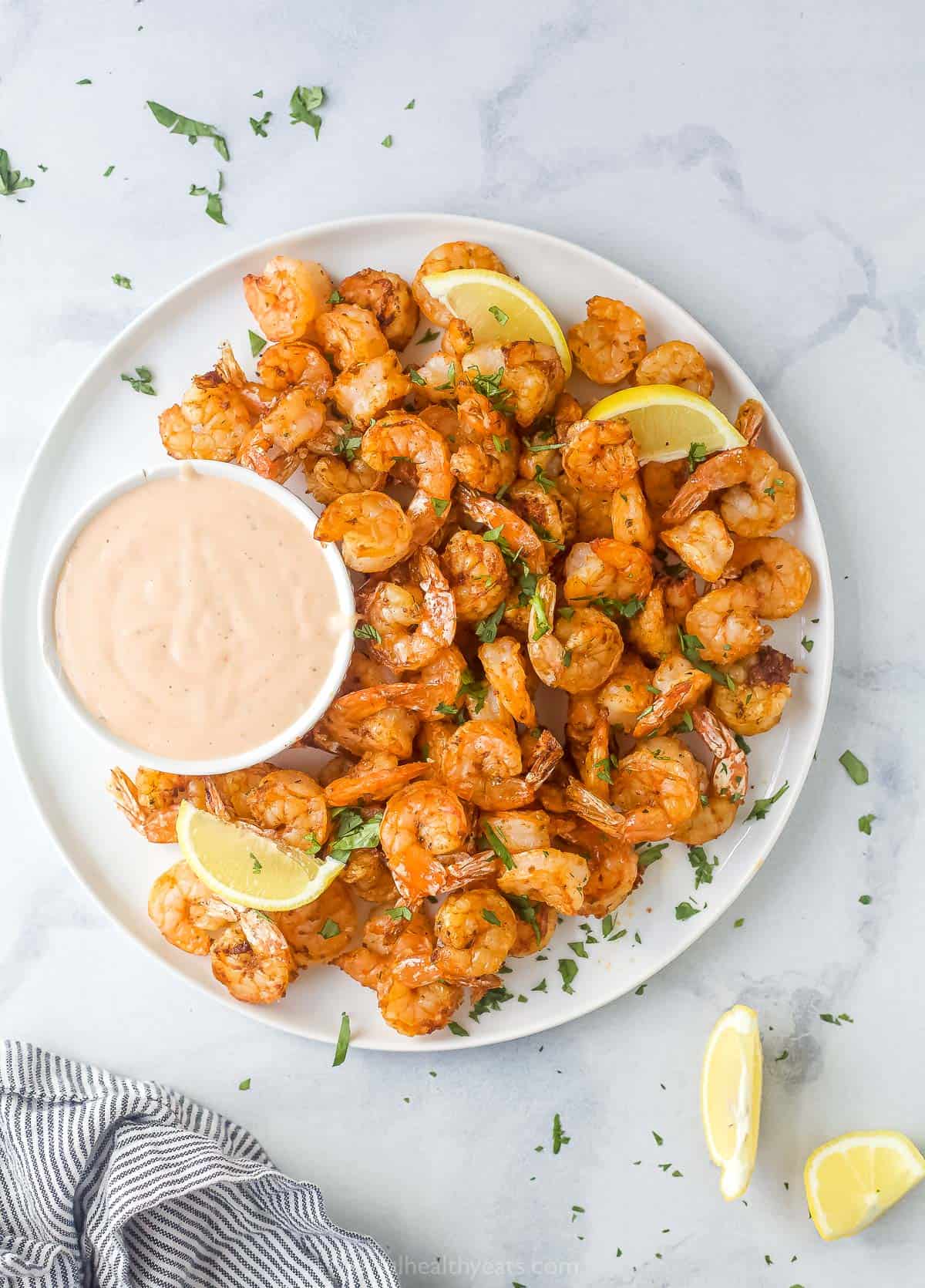 a plate of cooked shrimp with a side of dipping sauce