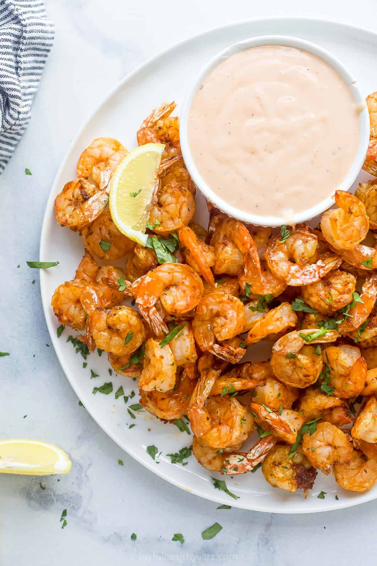 a plate of cooked shrimp with a side of dipping sauce