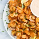 a plate of cooked shrimp with a side of dipping sauce