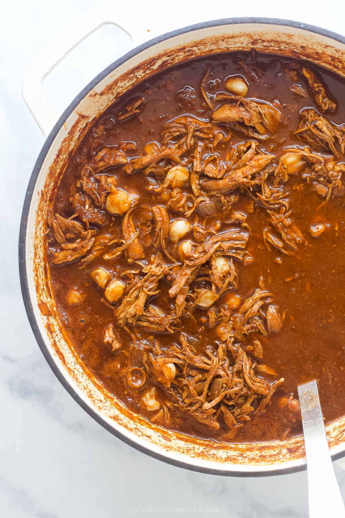 Mexican Chicken Stew with bits of pulled chicken and hominy in a brown broth