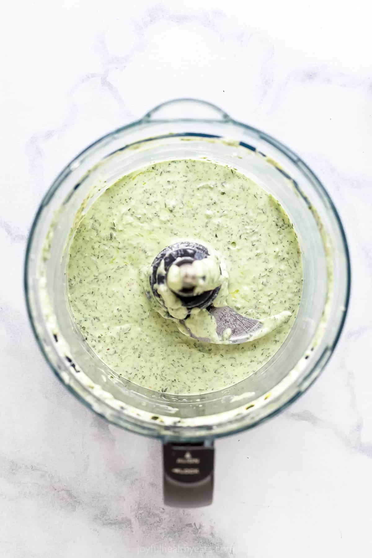 The fully blended dressing inside of a blender on a marble surface