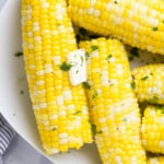 Pressure cooker corn on the cob topped with a pat of butter and a sprinkle of chopped herbs