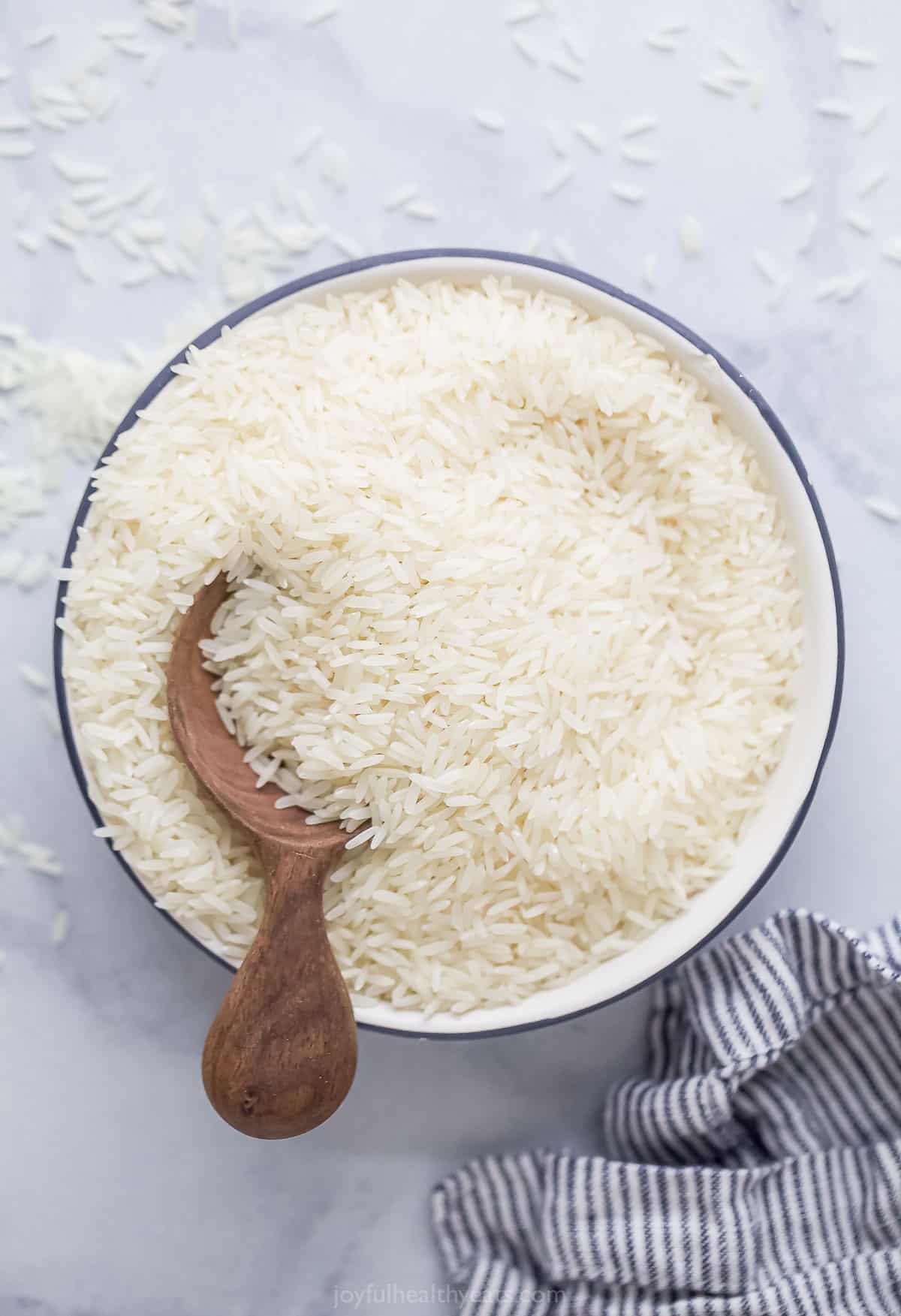 a large bowl of uncooked rice with a wooden spoon